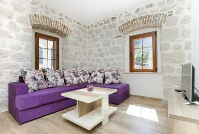 a living room with a purple couch and a table at Apartments Mezini 11 in Kotor