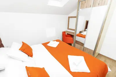 a bedroom with a bed with an orange blanket at Apartments Mezini 11 in Kotor