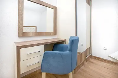 a blue chair sitting next to a dresser with a mirror at Apartments Mezini 11 in Kotor