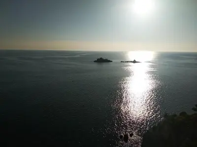 an island in the ocean with the sun in the sky at Studio Alexandra in Petrovac na Moru