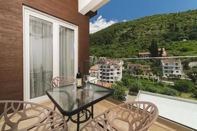 a glass table and chairs on a balcony with a view at Hotel 219 Budva in Budva