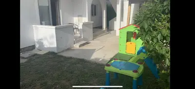 a toy house sitting in the grass next to a building at Apartments Dibra in Ulcinj