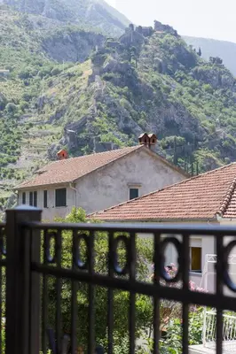 a view of a house from a fence with a mountain at ENA Apartment in Kotor