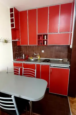 a red kitchen with red cabinets and a table at Sunčani apartman 1-Vila Amfora in Budva