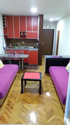 a room with purple beds and a table and a kitchen at Sunčani apartman 1-Vila Amfora in Budva