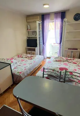 a room with two beds and a table and a window at Sunčani apartman 1-Vila Amfora in Budva
