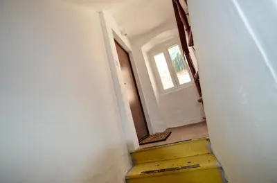 a hallway with a door and a yellow stairway at Portobello Old Town in Kotor