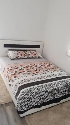 a bed with a black and white comforter and pillows at Apartmani Stijepovic in Podgorica