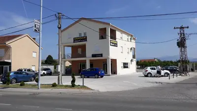 a white building with cars parked in a parking lot at Apartmani Stijepovic in Podgorica