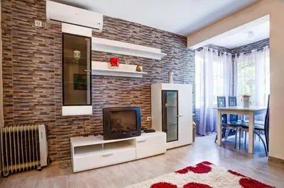 a living room with a tv and a brick wall at Stojkovic Family Apartments in Tivat