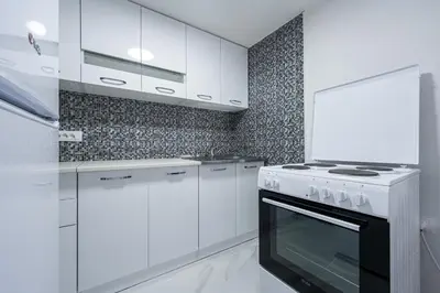 a white kitchen with white cabinets and a stove at Stojkovic Family Apartments in Tivat