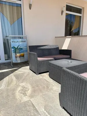 a patio with wicker chairs and a table and a sign at Villa Grand in Bar