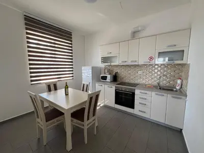 a kitchen with white cabinets and a table with chairs at Villa Grand in Bar