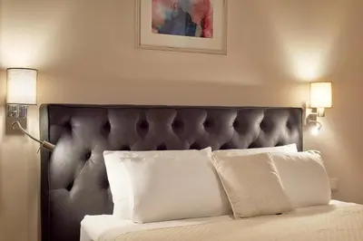 a bed with a black headboard and white pillows at 2montenegro HARMONIA APARTMENTS Becici in Becici