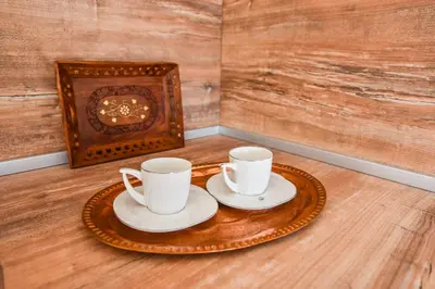 two white cups and saucers on a table with a fireplace at Dragovoja Lux Apartments & Rooms in Ulcinj