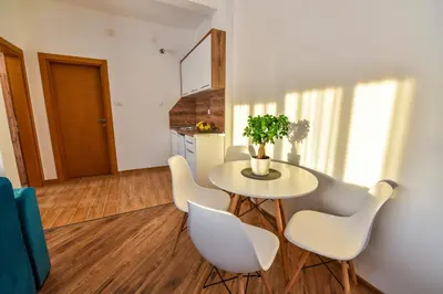 a dining room with a table and white chairs at Dragovoja Lux Apartments & Rooms in Ulcinj