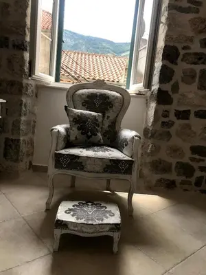 a chair and a stool in front of a window at New renovated Old Town Martiva Apartment in Kotor