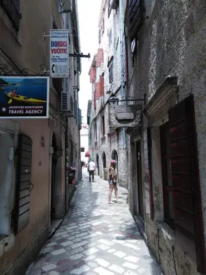 a woman walking down a street in an alley at New renovated Old Town Martiva Apartment in Kotor