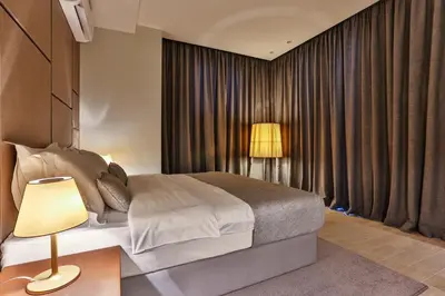 a bedroom with a bed and a lamp and curtains at Avanti Hotel & Spa in Budva