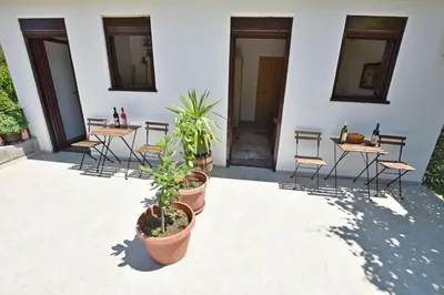 a patio with tables and chairs and potted plants at Rooms Sveti Toma in Virpazar