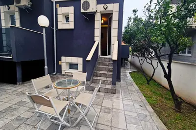 a patio with a table and chairs in front of a house at Basileus Apartments Budva in Budva