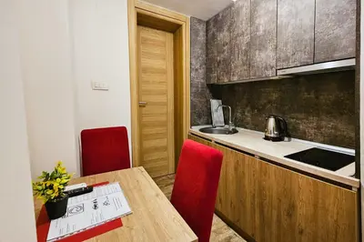 a kitchen with a wooden table and red chairs at Basileus Apartments Budva in Budva