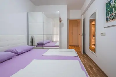 a bedroom with purple beds and a mirror at Bel Mare Apartments in Budva