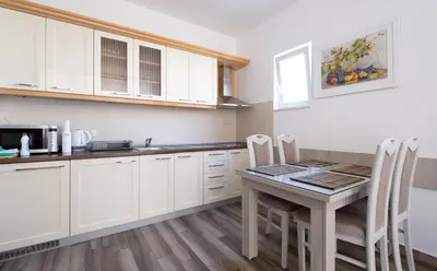 a kitchen with white cabinets and a table and chairs at Bel Mare Apartments in Budva