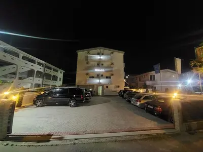a parking lot with cars parked in front of a building at Ulcin Relax Apartments & Rooms in Ulcinj