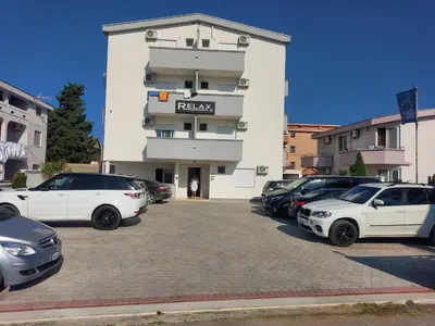 a parking lot with cars parked in front of a building at Ulcin Relax Apartments & Rooms in Ulcinj