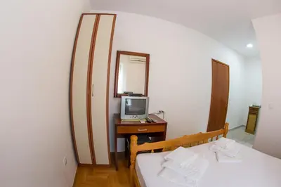 a bedroom with two beds and a television on a desk at Guesthouse Dapcevic in Budva