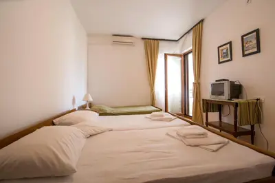 two beds in a hotel room with a tv at Guesthouse Dapcevic in Budva