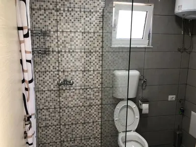 a bathroom with a toilet and a window at Stanovic Bungalow in Ulcinj