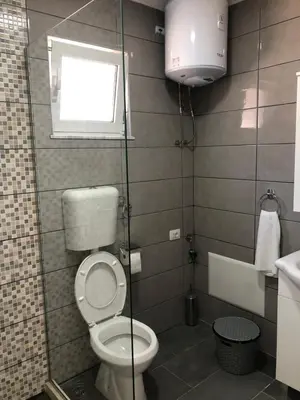 a bathroom with a toilet and a window and a sink at Stanovic Bungalow in Ulcinj