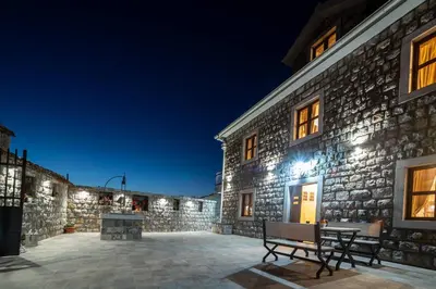a stone building with two benches on a patio at night at Villa Old Castle Apartments in Kotor