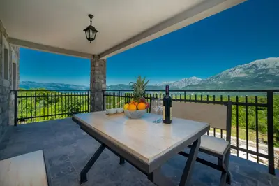 a table with a bottle of wine and fruit on a balcony at Villa Old Castle Apartments in Kotor
