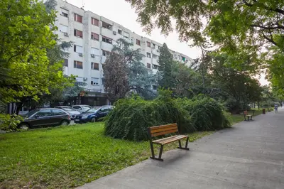 a park bench on a sidewalk next to a building at Apartman Preko Morace 2018 in Podgorica