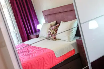 a small bedroom with a pink bed and a mirror at Apartment Anatolia Pekovic in Becici