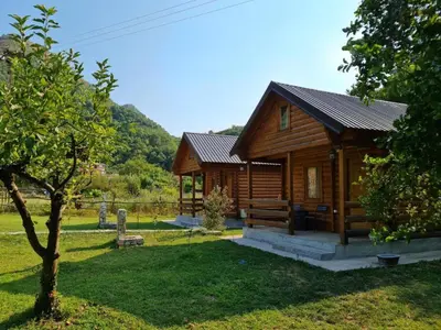 a log cabin in a field with a tree at Little Paradise in Virpazar