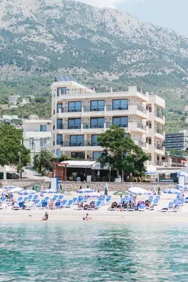 a hotel on a beach with chairs and the water at Sunset Hotel in Dobra Voda