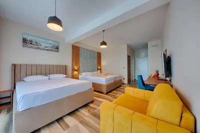 a hotel room with two beds and a couch at Sunset Hotel in Dobra Voda