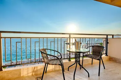 a balcony with a table and chairs and the ocean at Sunset Hotel in Dobra Voda