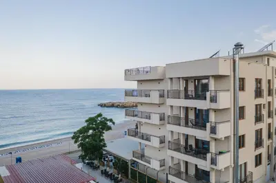a building next to a beach and the ocean at Sunset Hotel in Dobra Voda