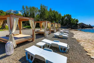 a row of beds and umbrellas on a beach at Zelen LUX in Sutomore