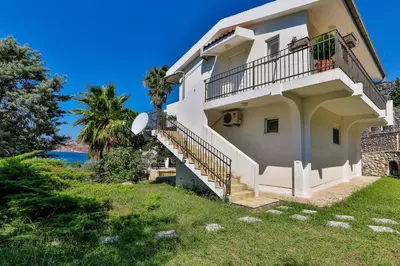 a white house with stairs and a palm tree at Zelen LUX in Sutomore