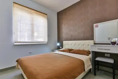 a bedroom with a bed and a desk and window at Zelen LUX in Sutomore