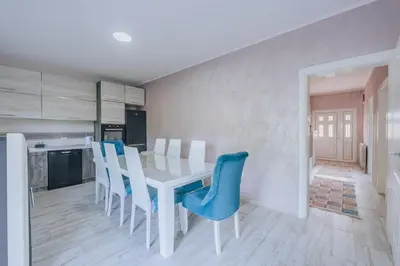 a kitchen with a white table and blue chairs at Apartment Majstorina in Virpazar