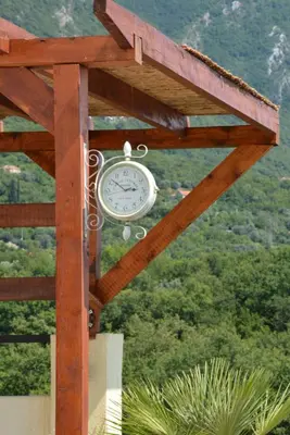 a clock is hanging from a wooden structure at Vila Pelinovo in Kotor