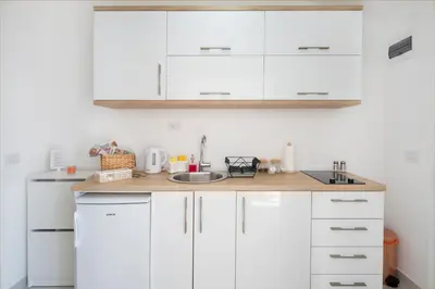 a kitchen with white cabinets and a sink at Dolores Apartments in Petrovac na Moru