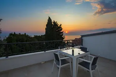 a balcony with a table and chairs and a sunset at Dolores Apartments in Petrovac na Moru